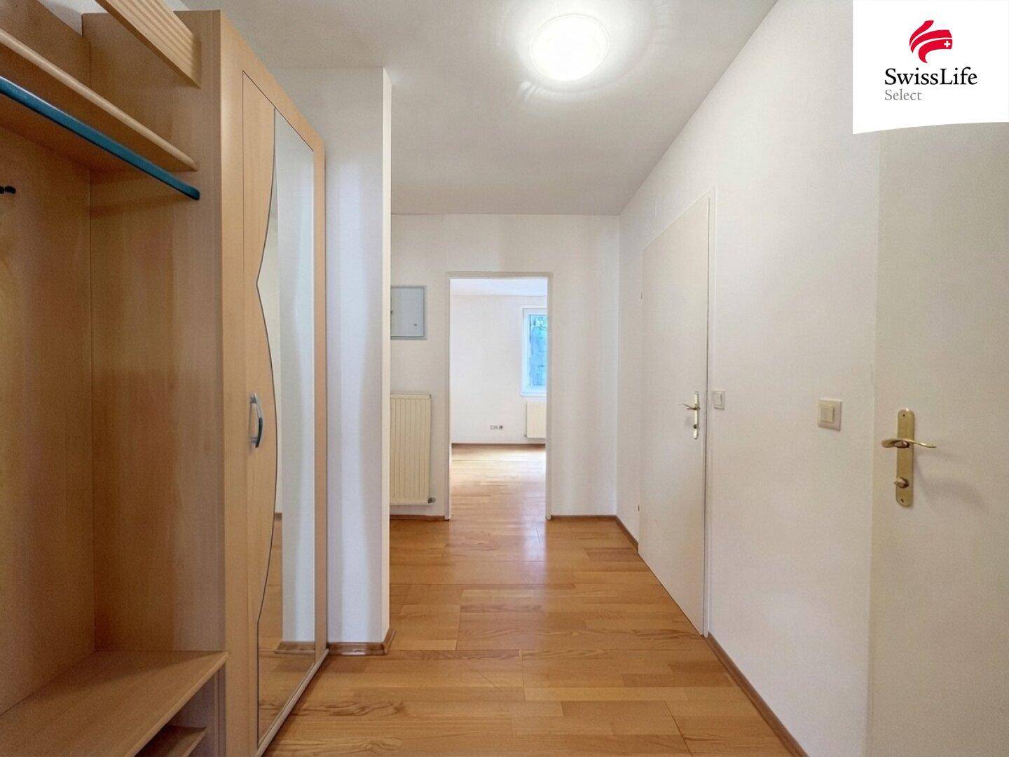 Langer Flur mit Holzboden und viel Tageslicht, der zu weiteren Räumen führt.