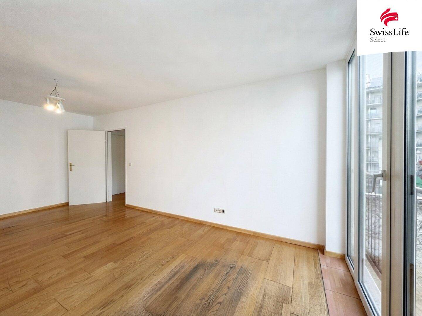 Geräumiges Wohnzimmer mit Holzboden und viel Tageslicht durch die großen Fensterfronten.
