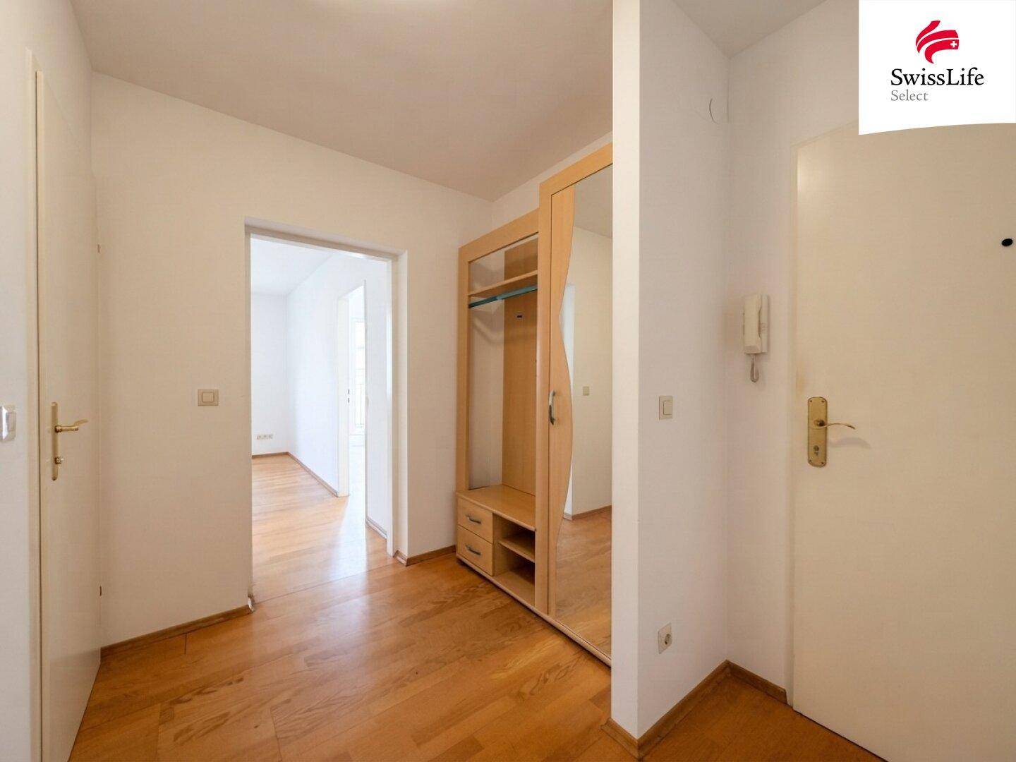 Eingangsbereich mit Parkettboden und einem praktischen Garderobenschrank mit Spiegel.