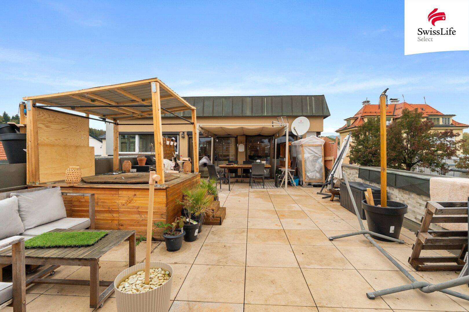 Weitläufige Dachterrasse mit Whirlpool, Lounge-Bereich und Blick auf die Umgebung.