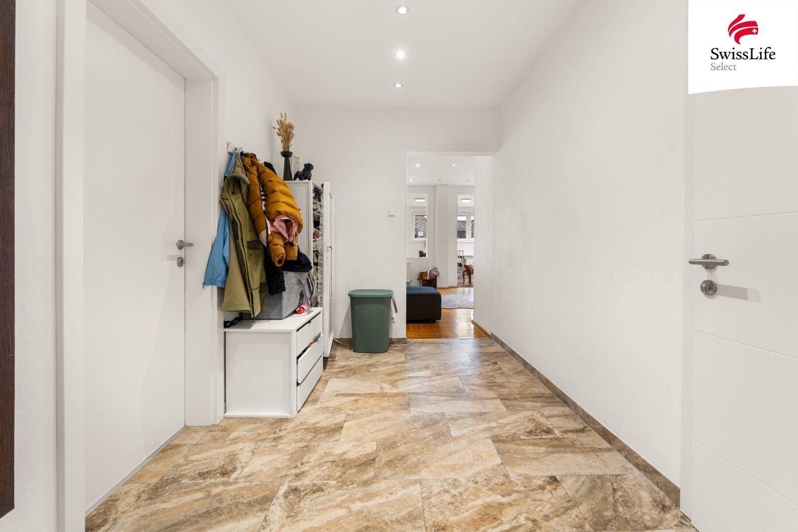 Heller Flur mit Fliesenboden, Garderobe und Zugang zu weiteren Räumen.