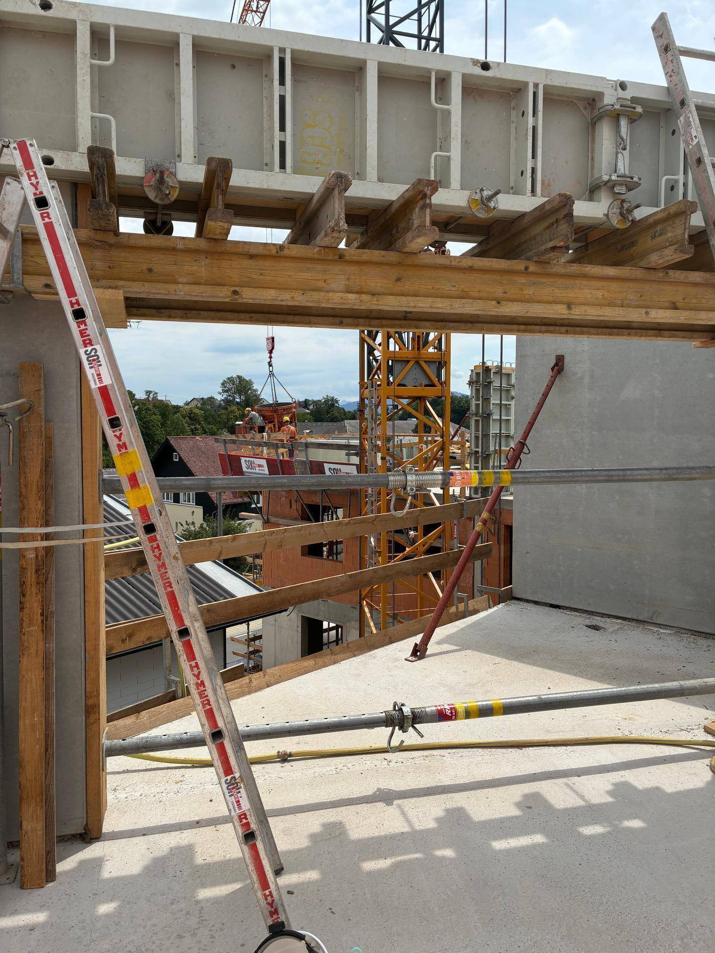 Baustelle mit Schalung, Gerüst und Kran im Hintergrund, Blick auf die Umgebung.