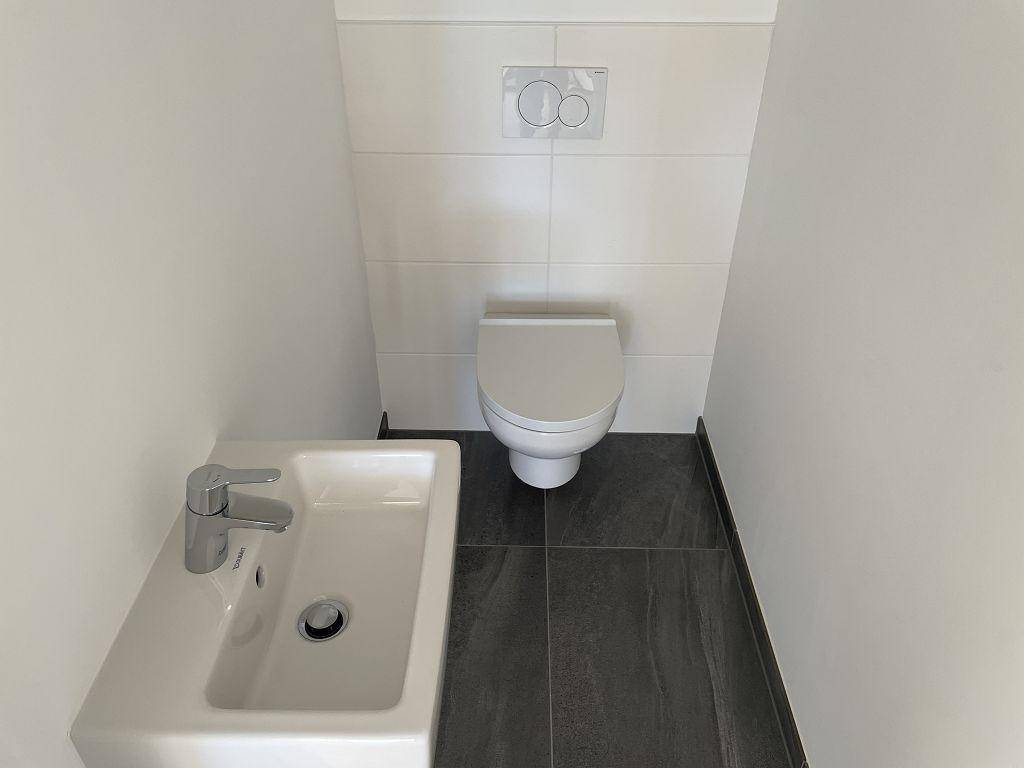 Kleines Gäste-WC mit wandhängender Toilette und modernem Waschbecken.