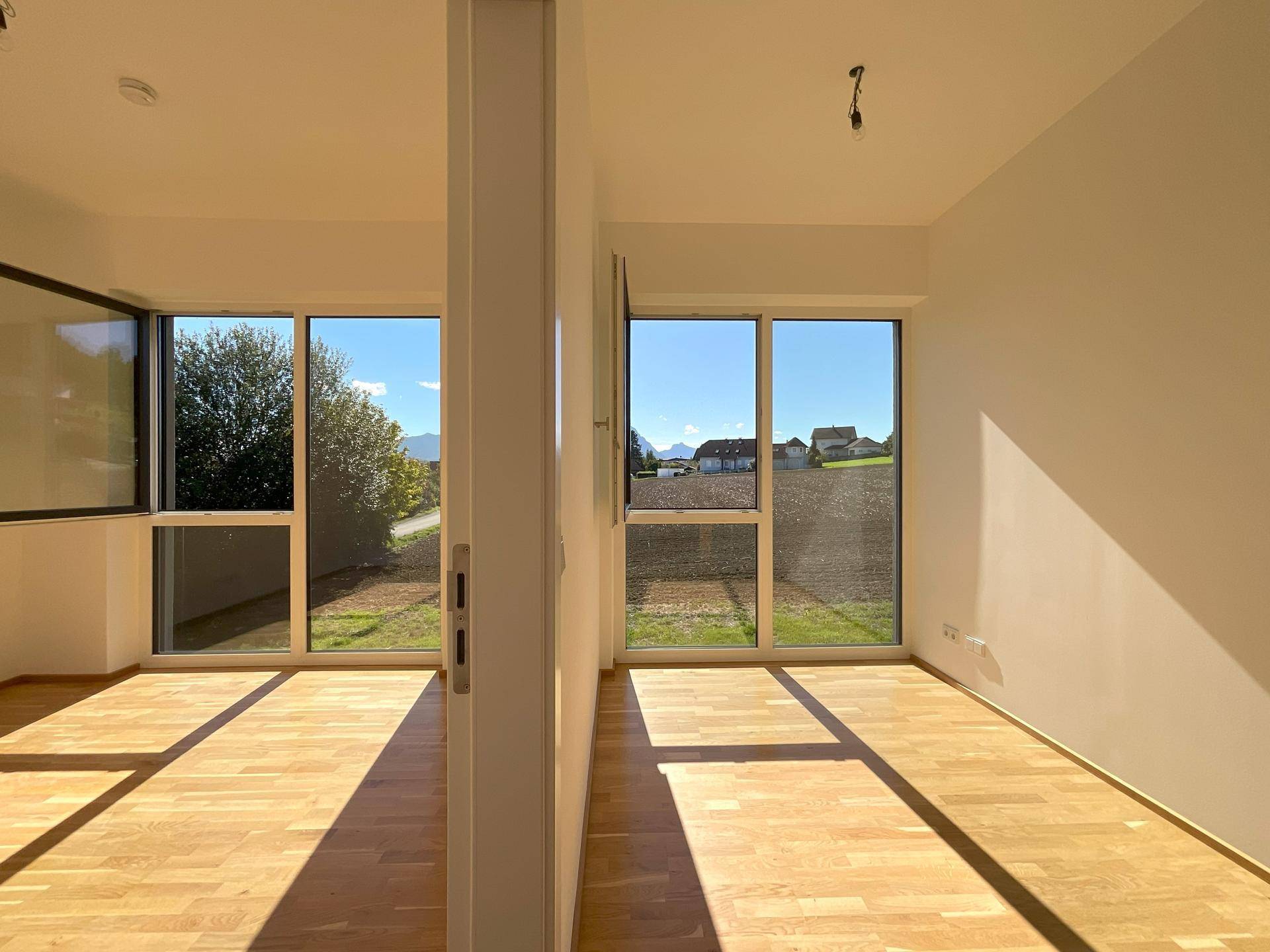 Leerer Raum mit großen Fenstern, die viel Tageslicht und einen weiten Blick bieten.