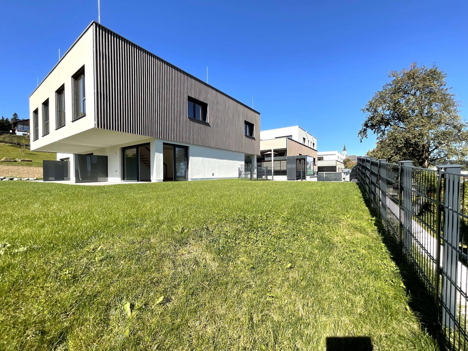 Modernes Gebäude mit großem Garten und weitem Blick in die Landschaft.