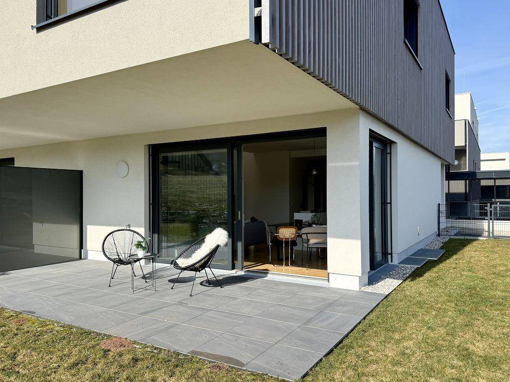 Große, gepflasterte Terrasse mit modernen Gartenmöbeln und angrenzendem Rasenbereich.