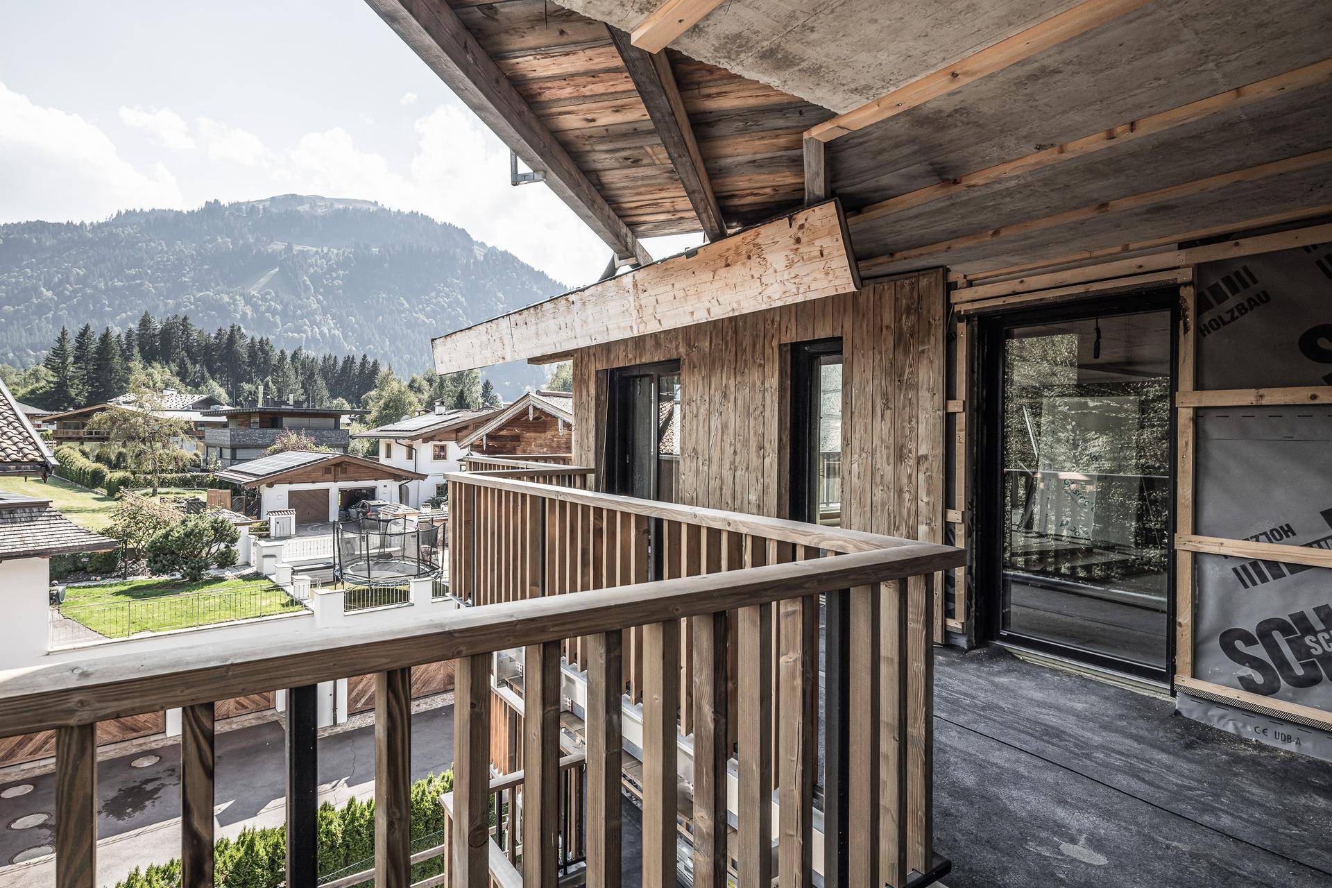 Geräumiger Balkon mit Holzboden und Geländer, bietet einen weiten Blick auf die umliegende Berglandschaft.