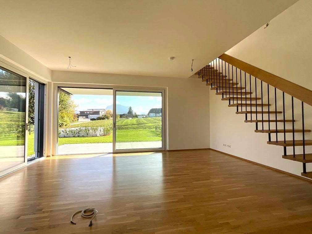 Geräumiger, leerer Wohn- und Essbereich mit großen Fenstern und Zugang zur Terrasse.