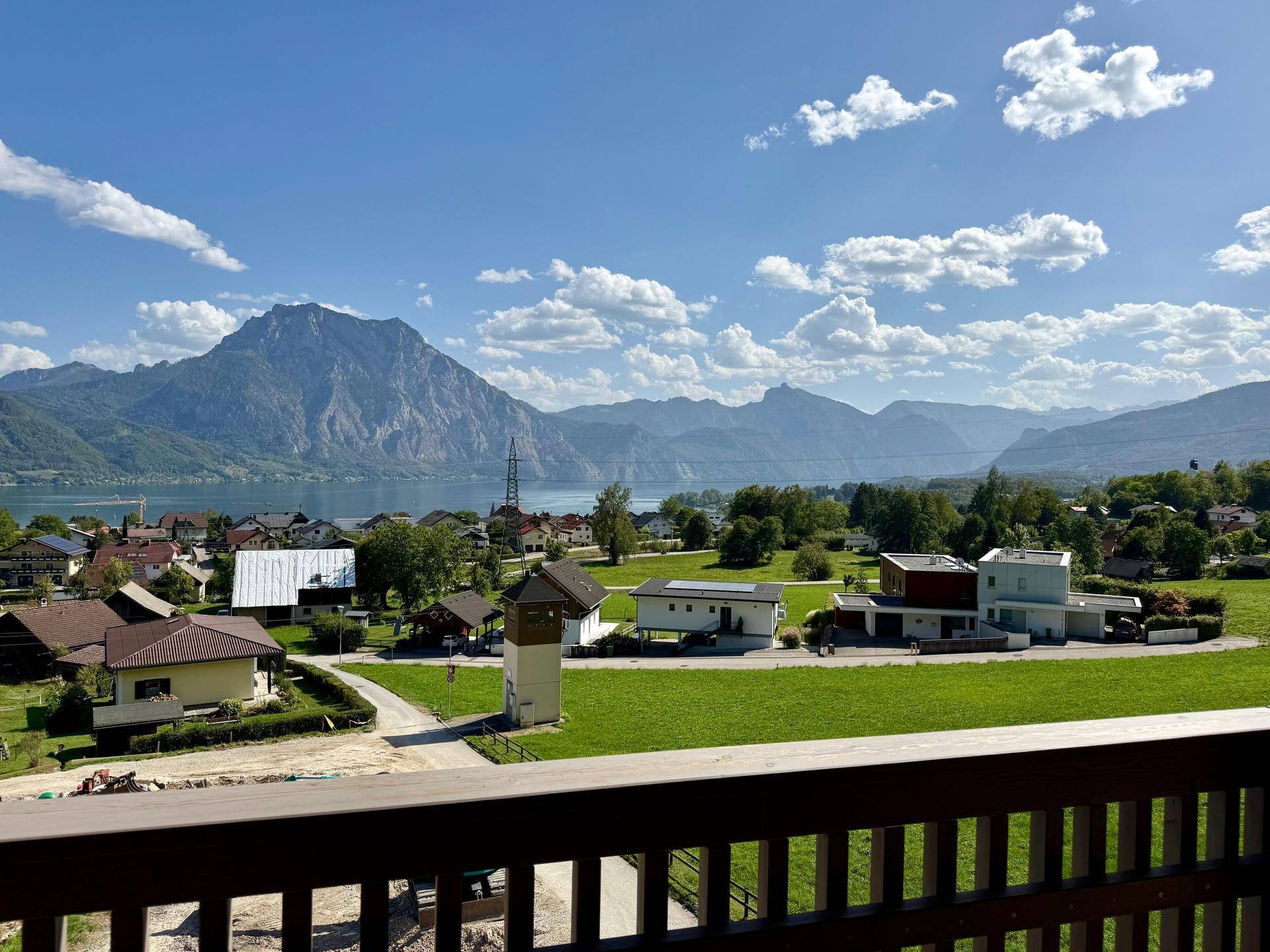 Weitläufiger Ausblick von einem Balkon über eine Seenlandschaft und umliegende Berge.