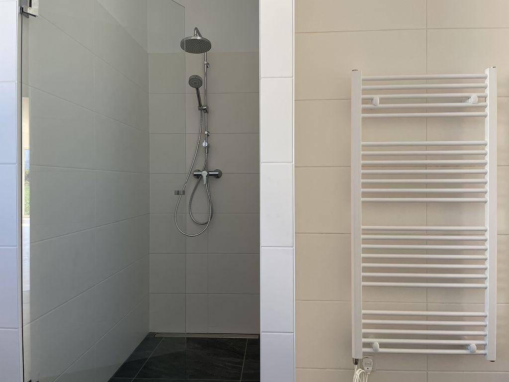 Modernes Badezimmer mit ebenerdiger Dusche, Regenduschkopf und praktischem beheiztem Handtuchhalter.