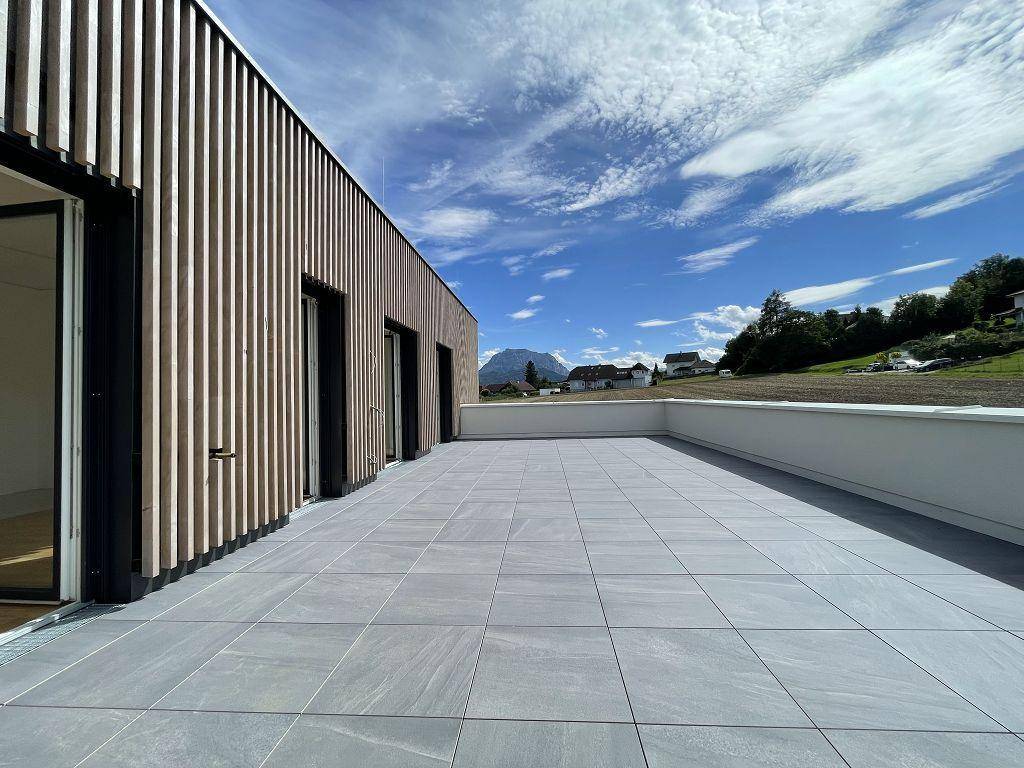 Geräumige, leere Dachterrasse mit modernen Fliesen und Holzfassade, bietet weite Ausblicke.