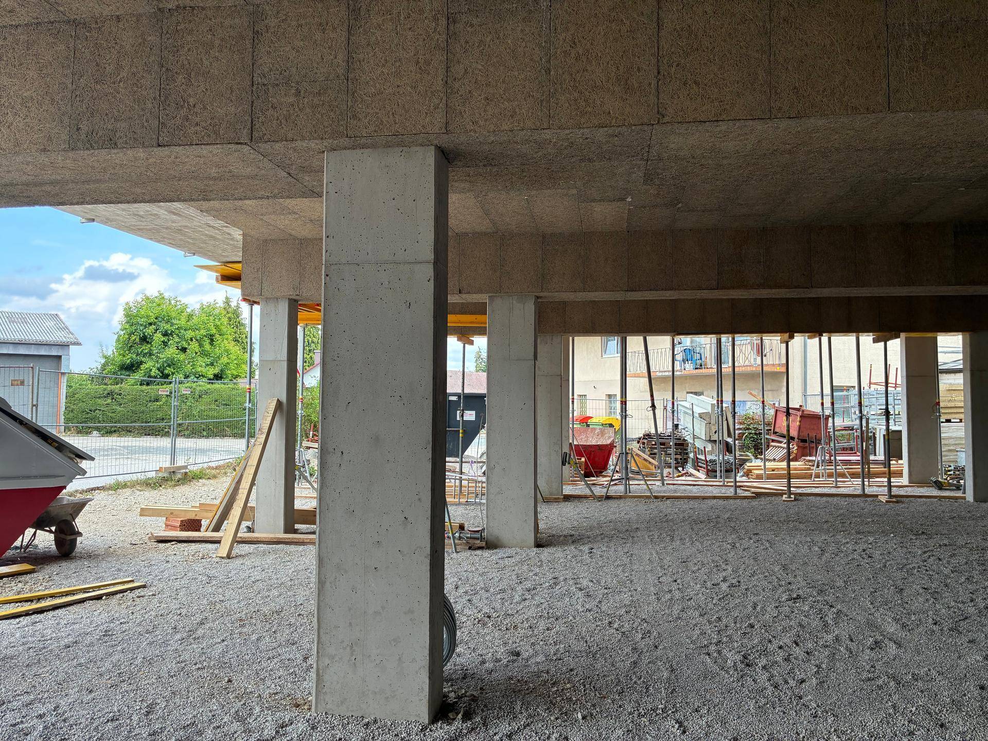 Rohbau mit Betonsäulen und Holzstützen, Blick nach draußen auf die Baustelle.
