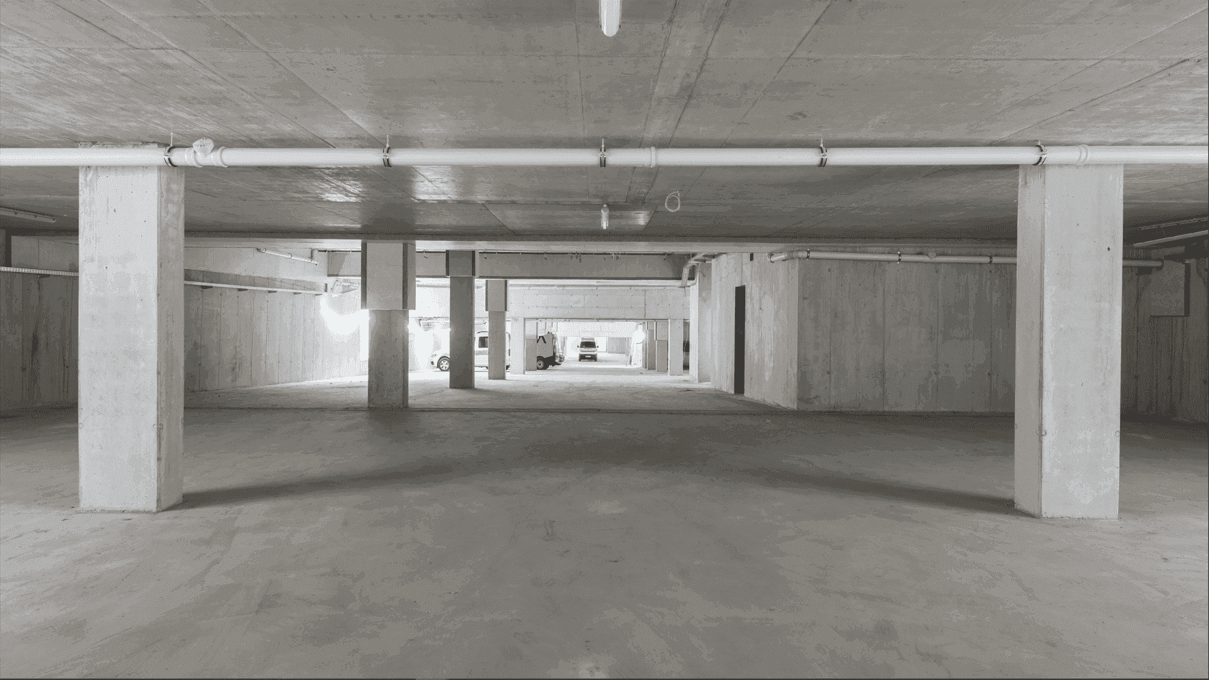 Geräumige Tiefgarage mit Betonwänden und -säulen, bereit für die Nutzung.