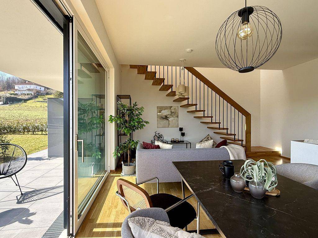 Offener Wohn- und Essbereich mit Holzboden, moderner Einrichtung und Zugang zur Terrasse.