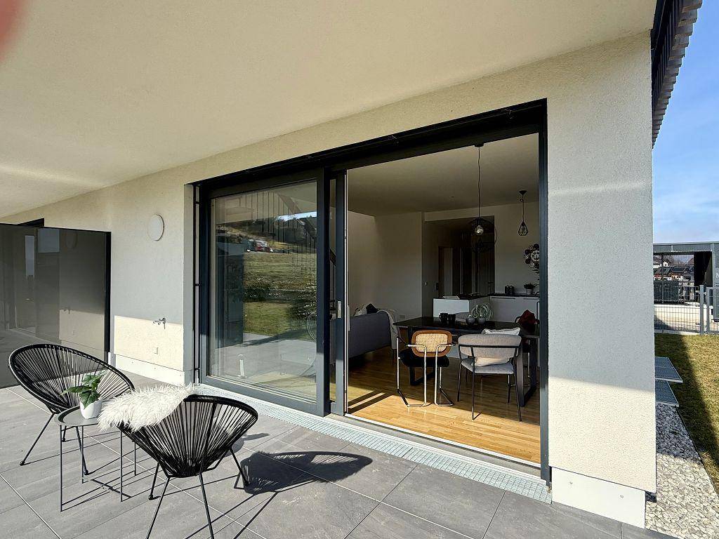 Sonniger Terrassenbereich mit modernen Sitzgelegenheiten und Blick ins Grüne.
