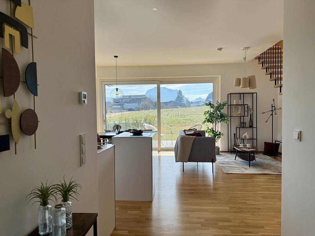 Heller Wohnbereich mit Holzboden, moderner Einrichtung und weitem Blick auf die Landschaft.