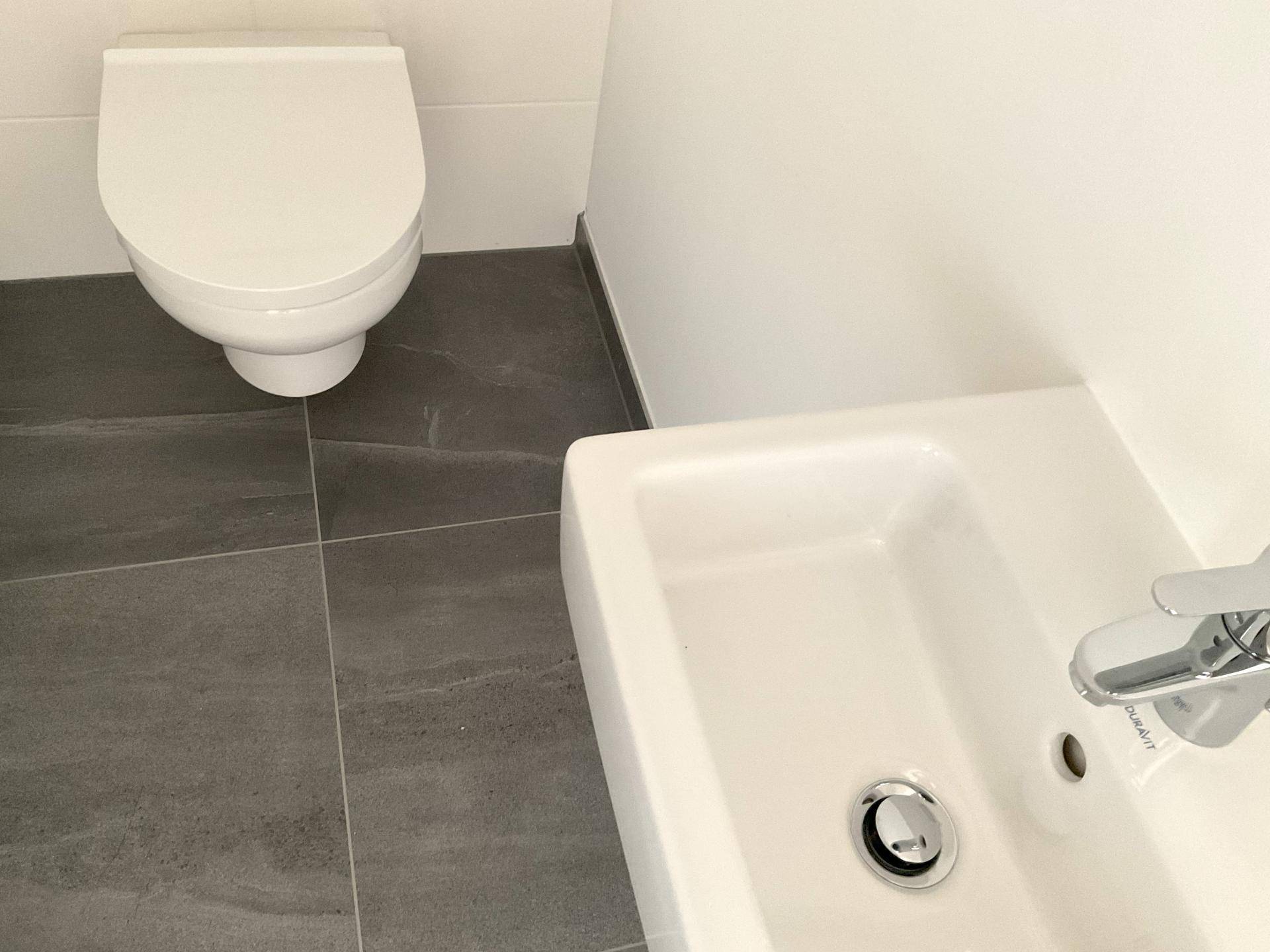 Modernes Gäste-WC mit wandhängender Toilette und kleinem Waschbecken.