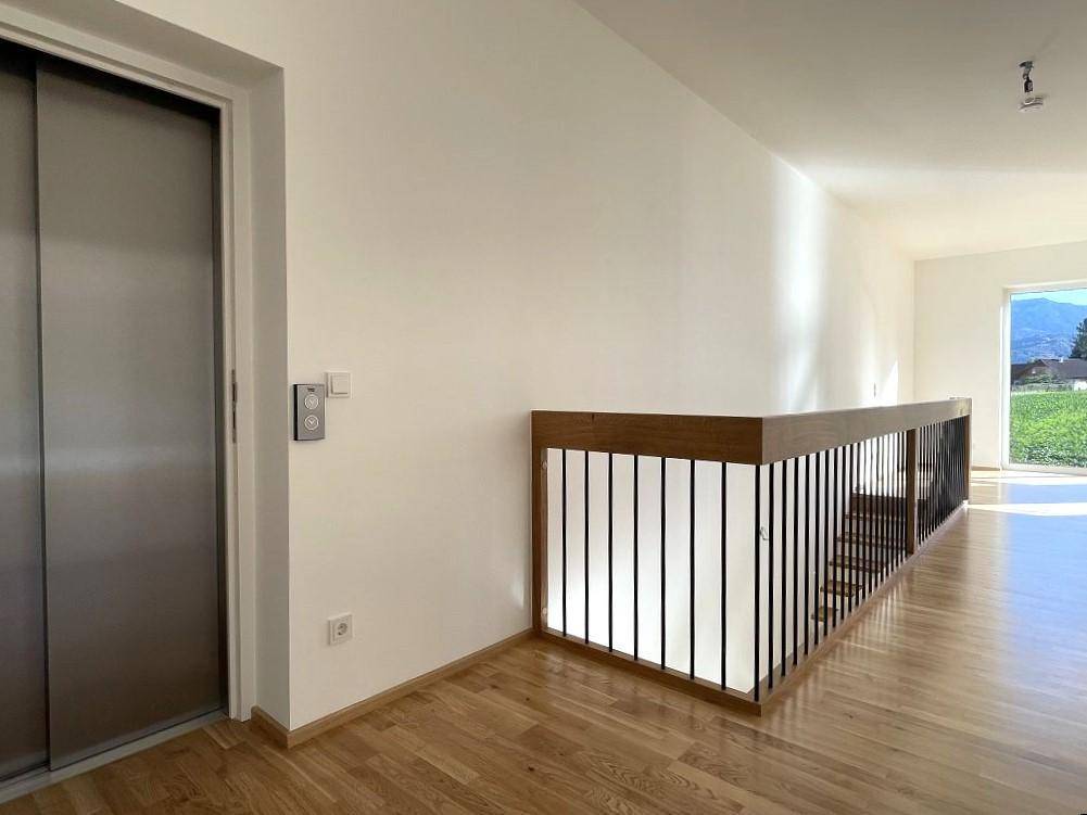 Heller Flur mit Holzboden, modernem Geländer und Aufzug, bietet einen weiten Ausblick.