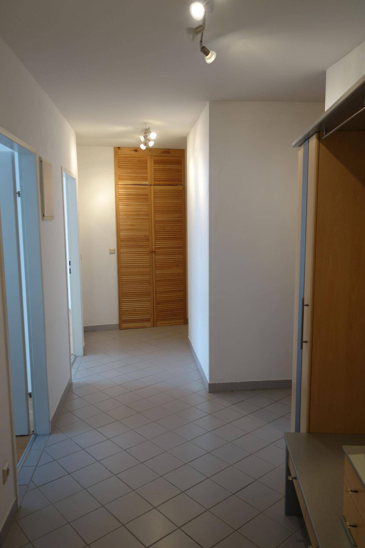 Heller Flur mit Fliesenboden und integrierten Schränken, verbindet verschiedene Wohnbereiche.