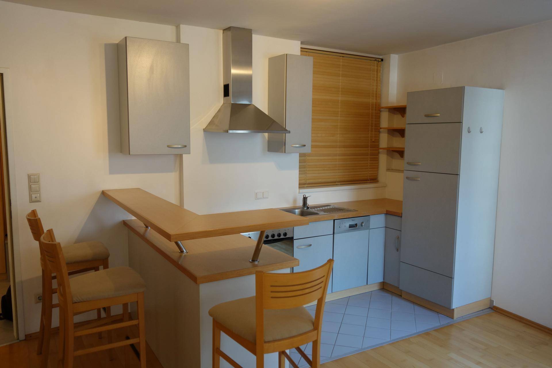 Funktionale Küche mit grauen Schränken, integriertem Essbereich und modernen Geräten.