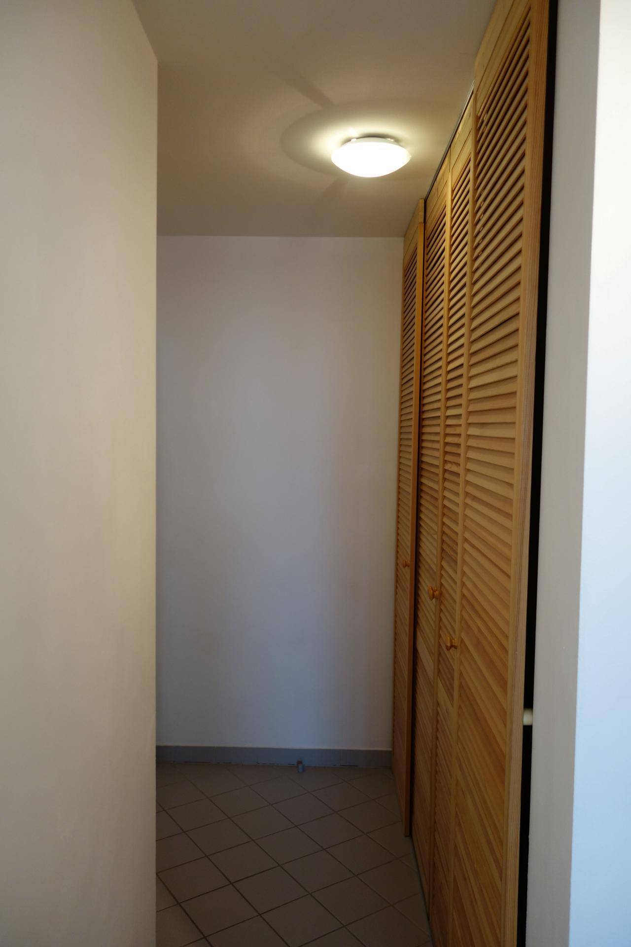 Schmaler Flur mit integrierten Holzschränken und Fliesenboden, bietet Stauraum.
