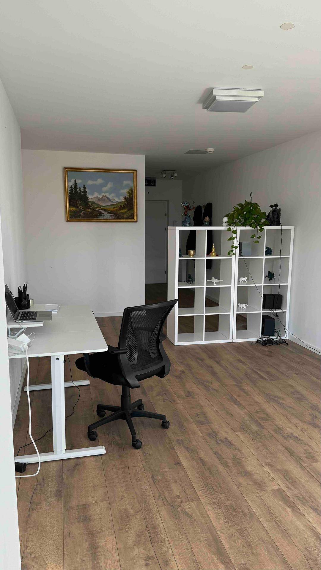 Heller Büroraum mit modernem Schreibtisch, Bürostuhl und weißem Regal, ideal für konzentriertes Arbeiten.