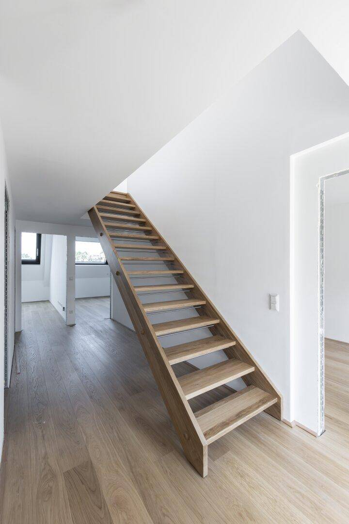 Heller Flur mit Holztreppe und Holzboden, der die verschiedenen Ebenen der Wohnung verbindet.