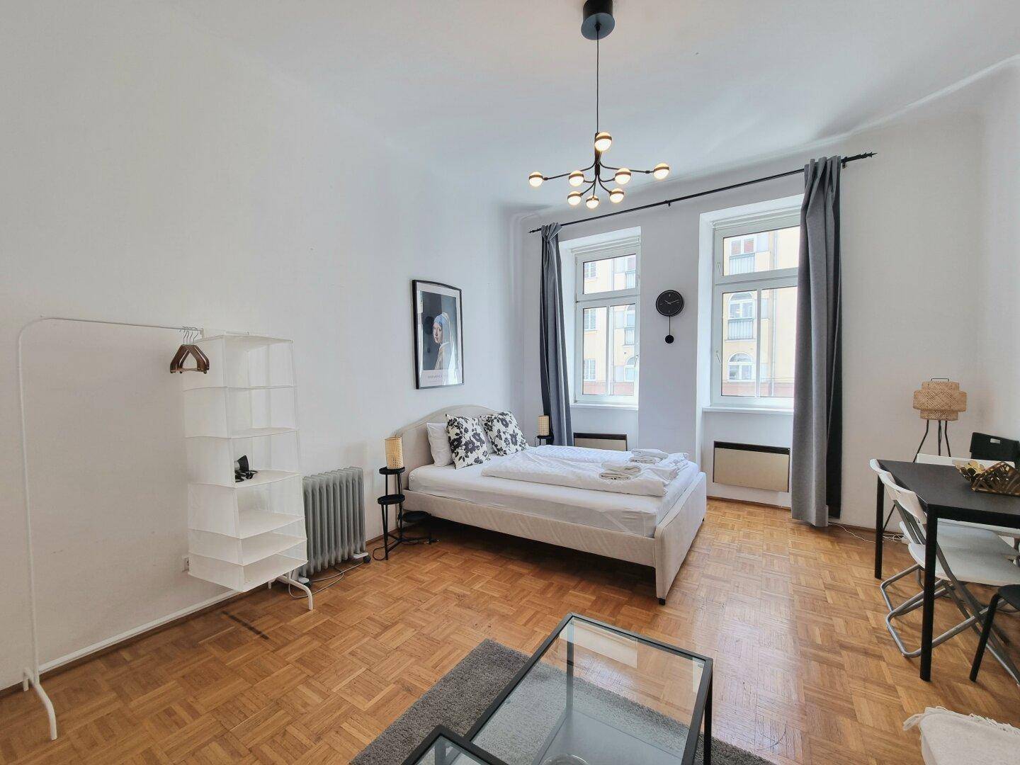 Geräumiges Studio mit Parkettboden, Schlafbereich und moderner Einrichtung.