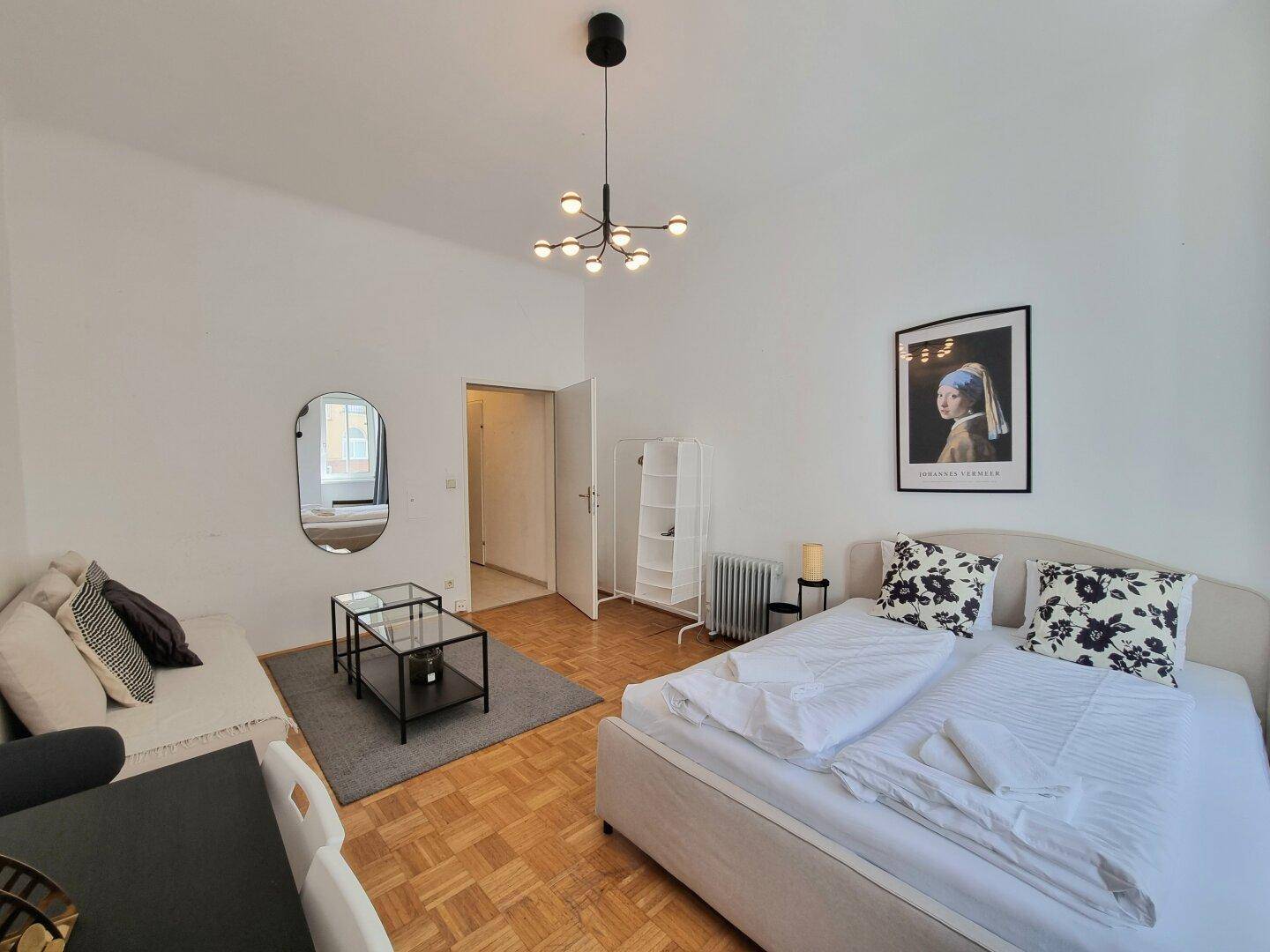 Lichtdurchflutetes Studio-Apartment mit Schlafsofa, Bett und Parkettboden.