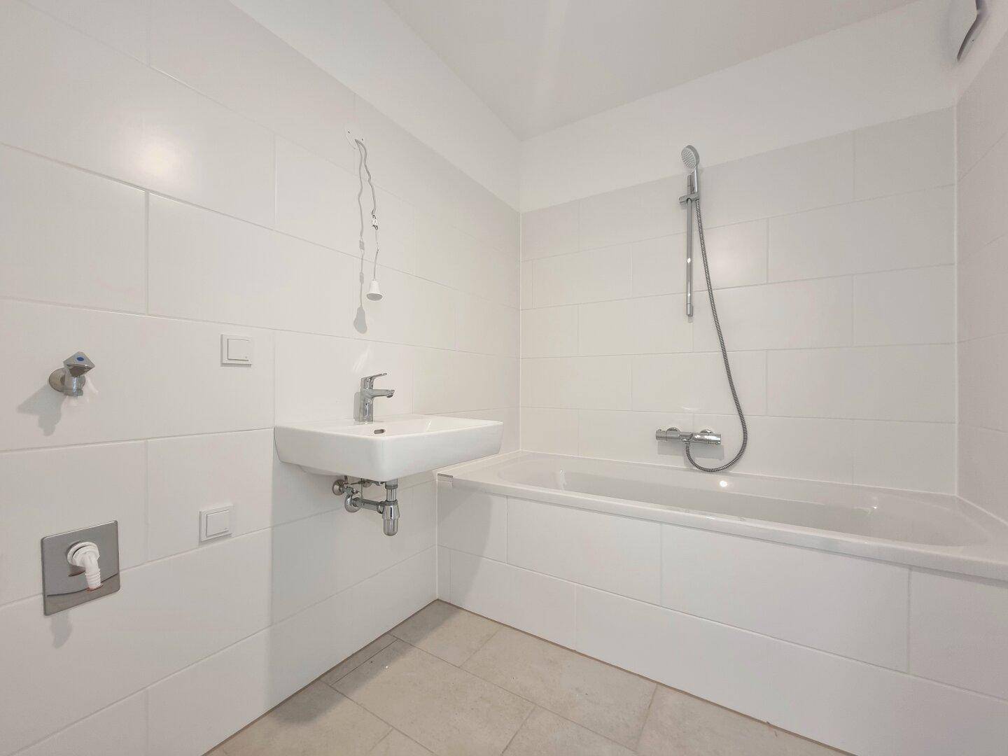 Modernes Badezimmer mit Badewanne, Waschbecken und weißen Fliesen, in mint-condition.