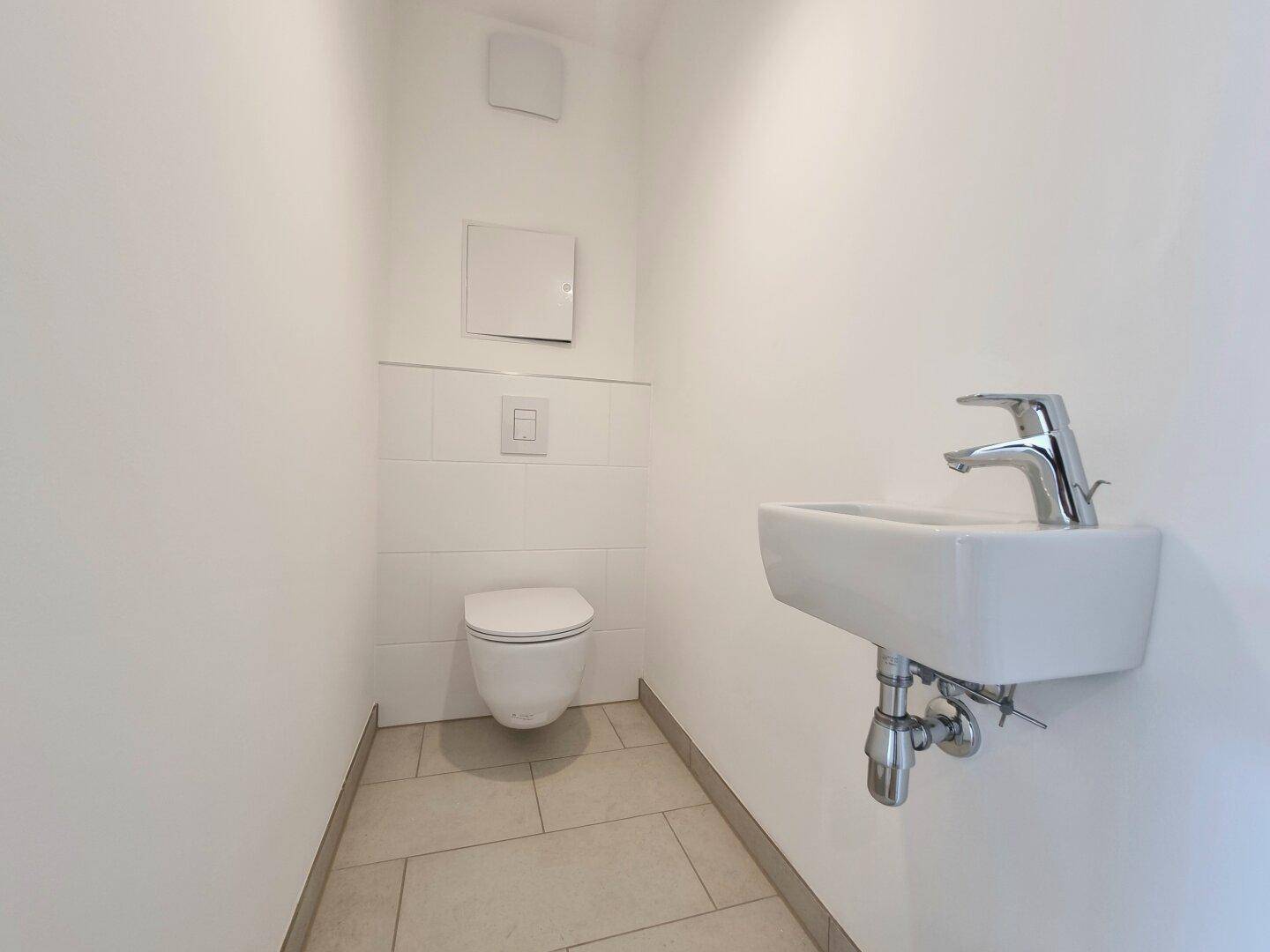 Kleines Gäste-WC mit wandhängender Toilette und modernem Waschbecken, sehr gepflegt.