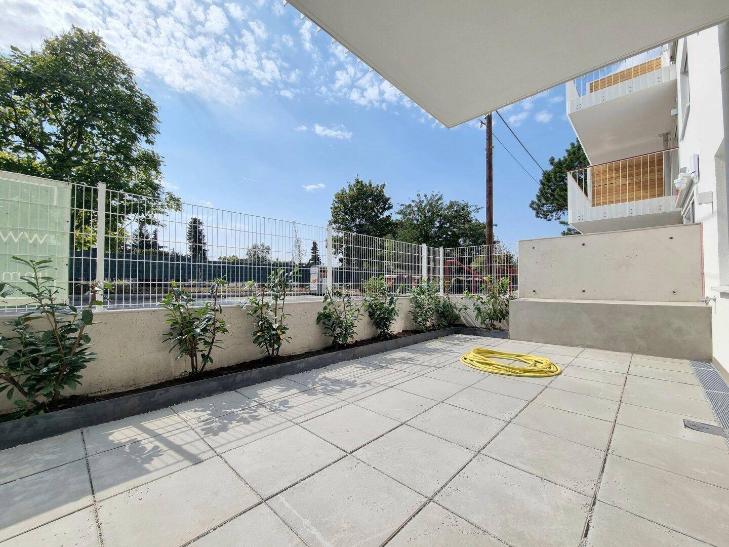 Geräumige Terrasse mit Fliesenboden und Blick ins Grüne, ideal zum Entspannen.