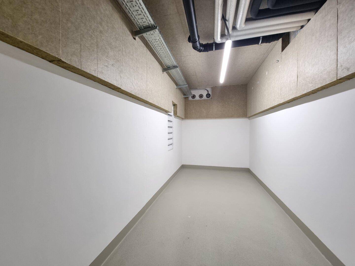 Heller Abstellraum im Keller mit glattem Boden und weißen Wänden, ideal für Lagerung.