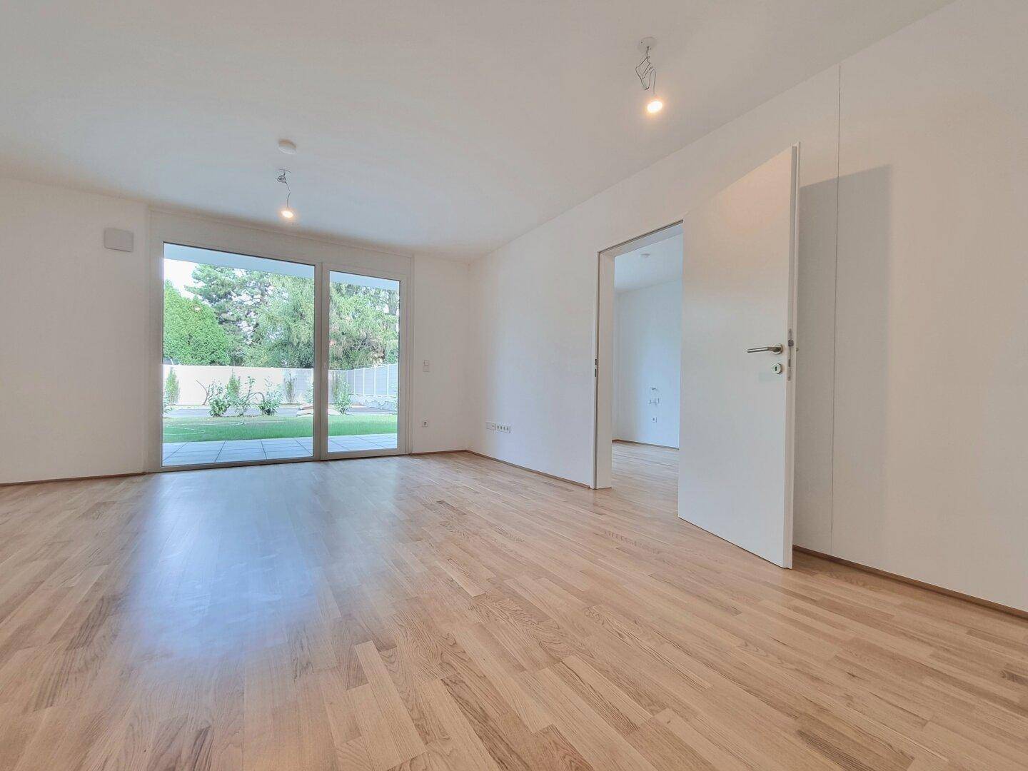 Helles Wohnzimmer mit Parkettboden und großen Schiebetüren zum Garten.