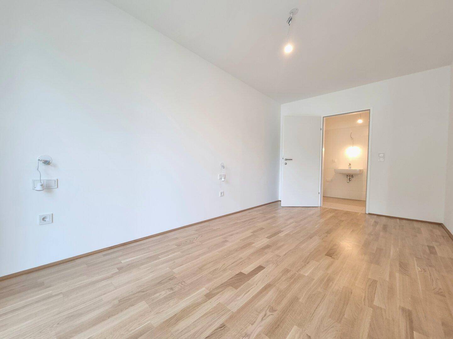 Schlafzimmer mit Parkettboden und direktem Zugang zu einem Badezimmer.
