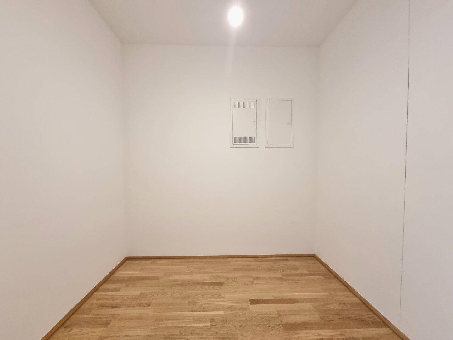 Kleinerer Raum mit Parkettboden und weißen Wänden, ideal als Kinder- oder Arbeitszimmer.