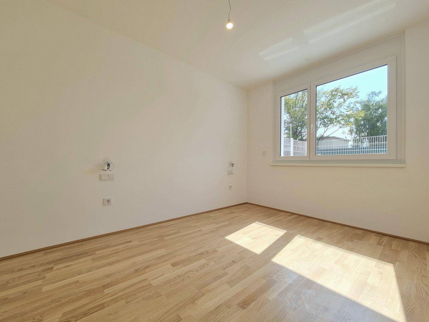 Schlafzimmer mit Parkettboden und großem Fenster für viel Tageslicht.