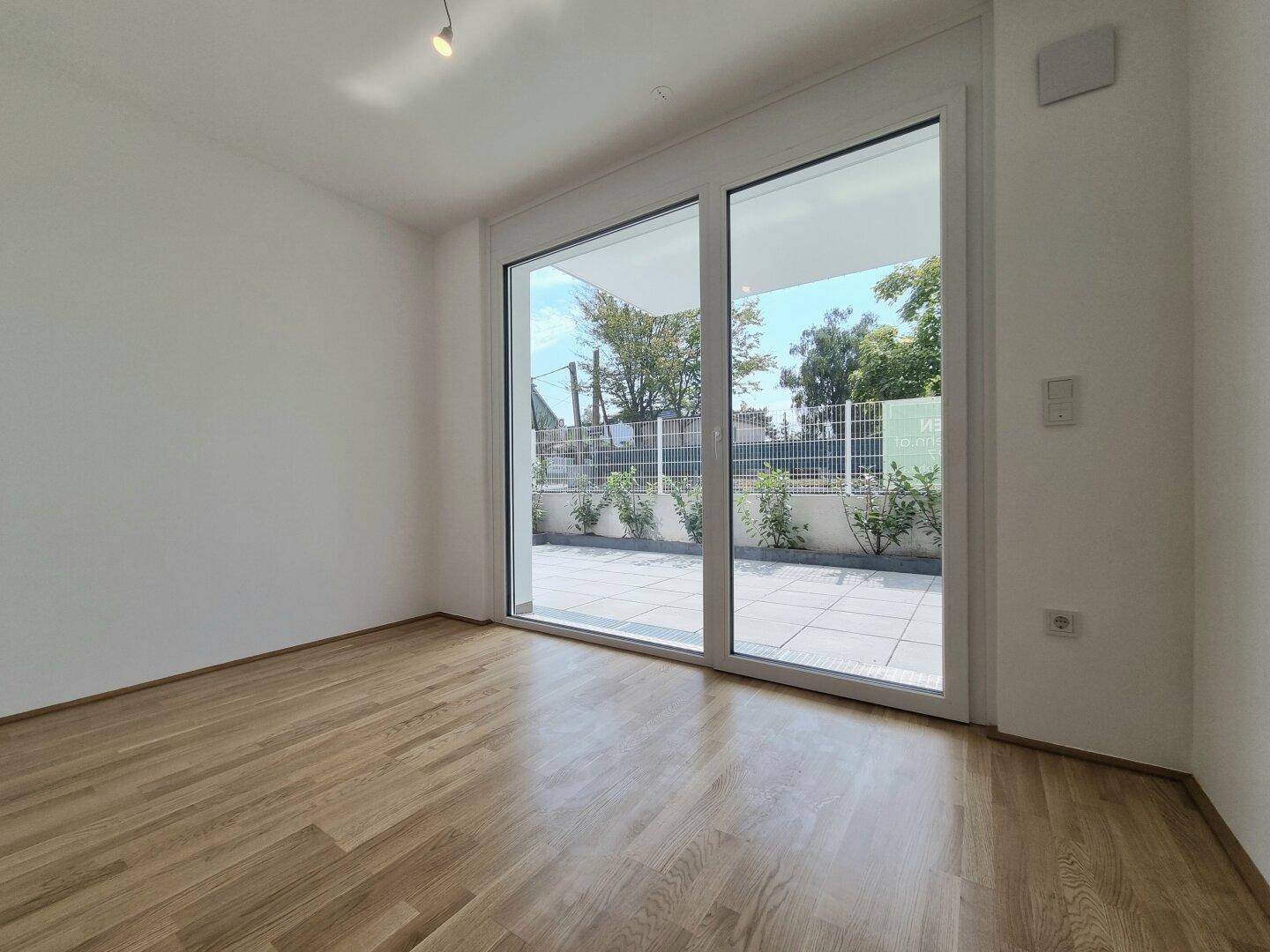 Schlafzimmer mit Parkettboden und Zugang zur Terrasse oder zum Garten.