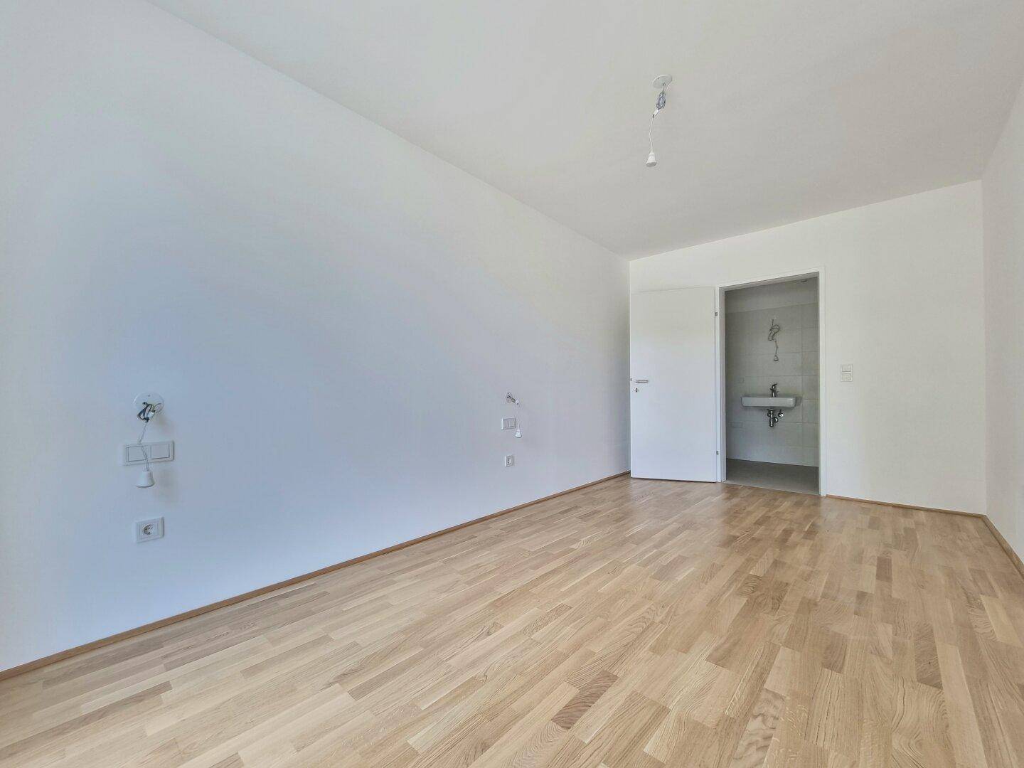 Schlafzimmer mit Holzboden und Zugang zu einem modernen Badezimmer, ideal für ein Ensuite-Erlebnis.