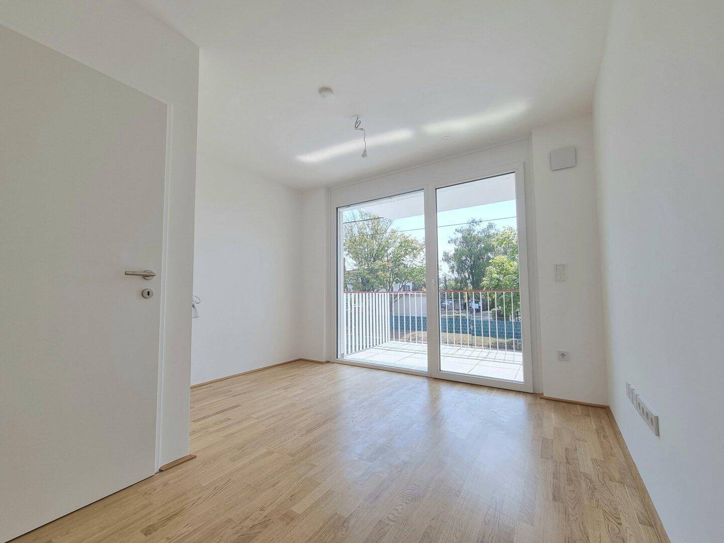 Geräumiges Schlafzimmer mit Holzboden und großer Glasschiebetür, die direkten Zugang zum Balkon bietet.