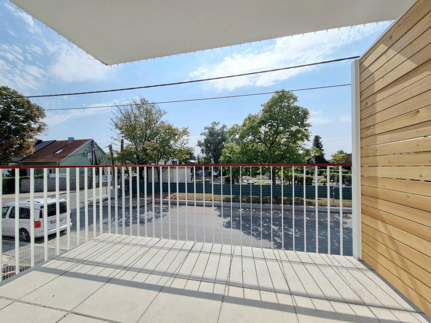 Moderner Balkon mit Fliesenboden und Holzwandverkleidung, bietet einen Blick auf die Straße.