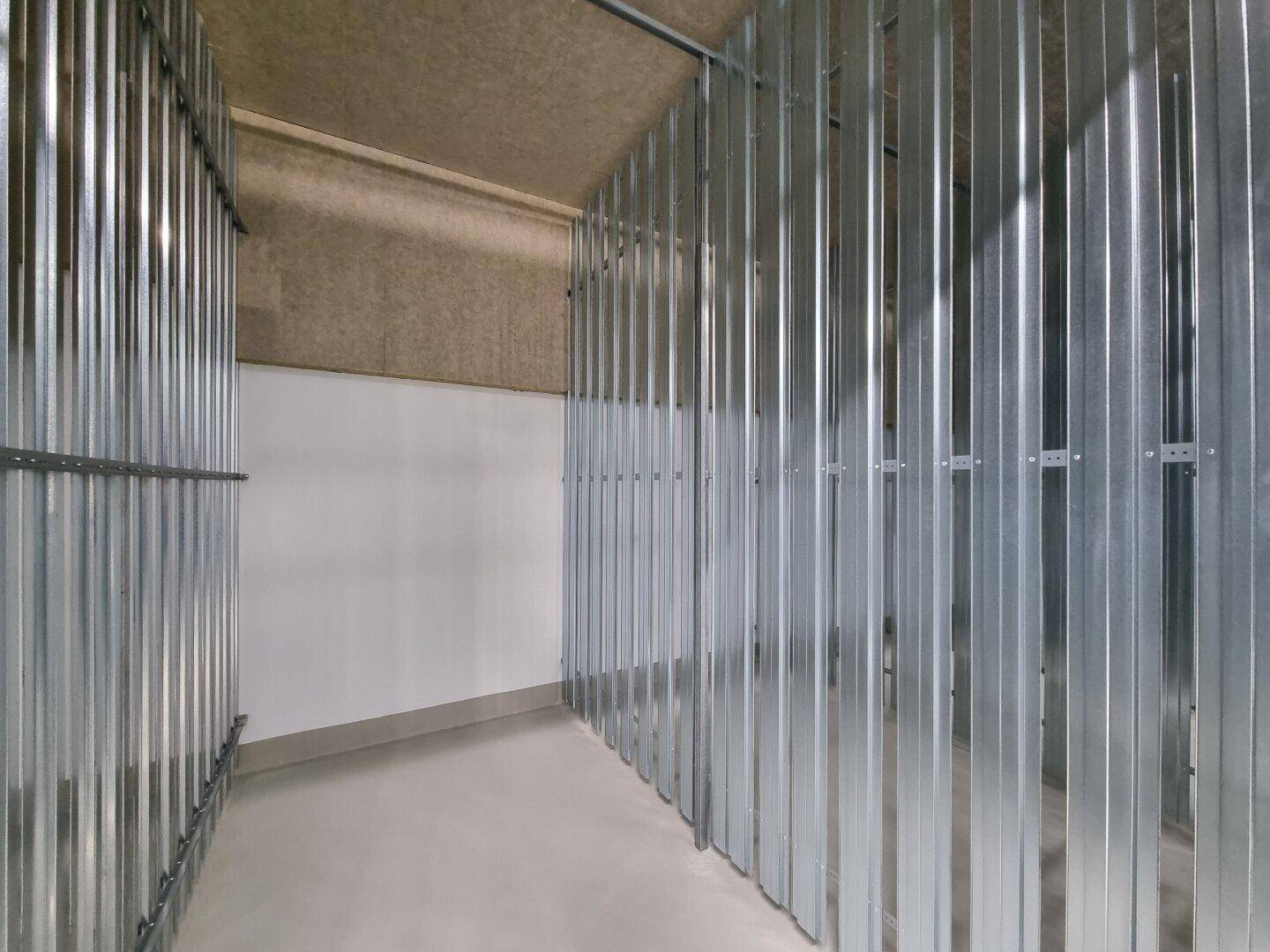 Individuelle Abstellräume im Keller, durch Metallwände getrennt, bieten sicheren Stauraum.