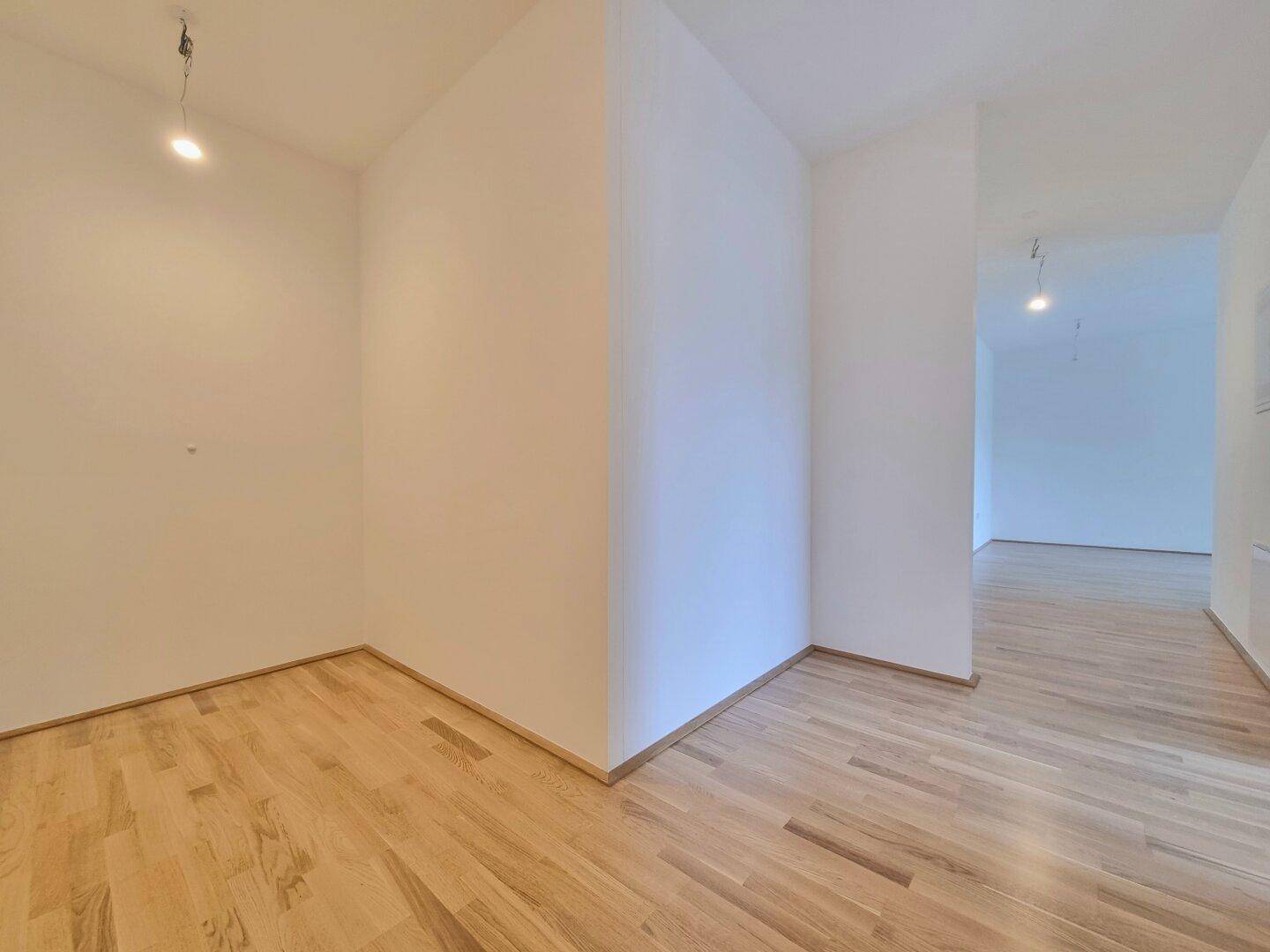 Heller Flurbereich mit Holzboden, der zu weiteren Zimmern der Wohnung führt.