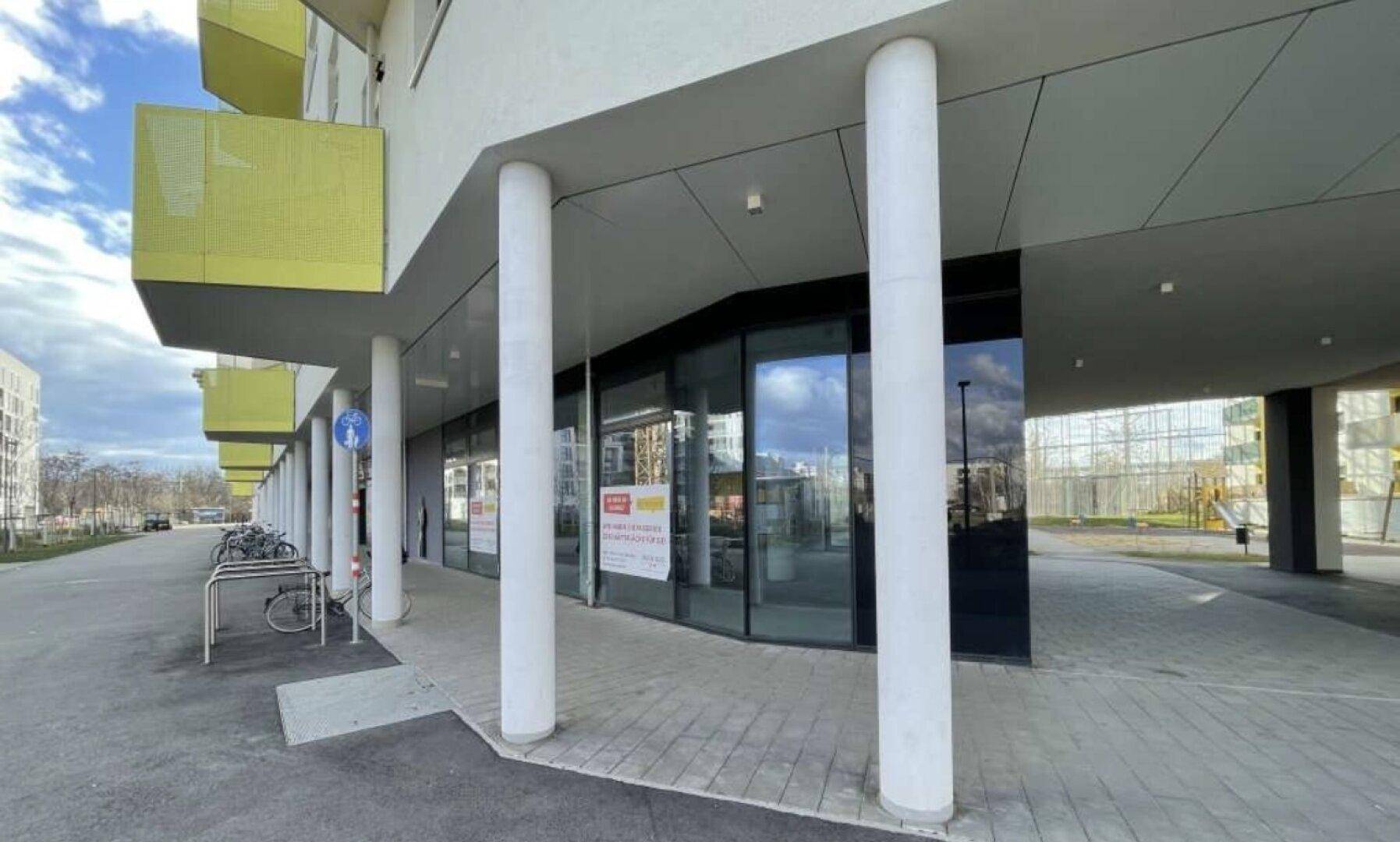Eingangsbereich eines modernen Gewerberaums im Erdgeschoss mit Glasfassade und Säulen.