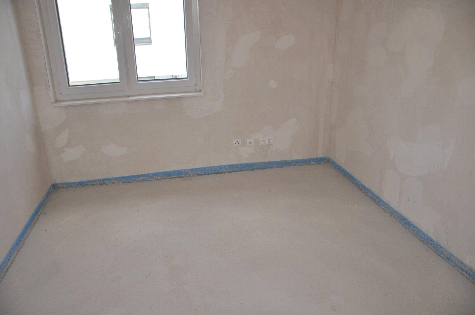 Unfertiges Zimmer mit Fenster und Steckdosen, bereit für die individuelle Gestaltung.