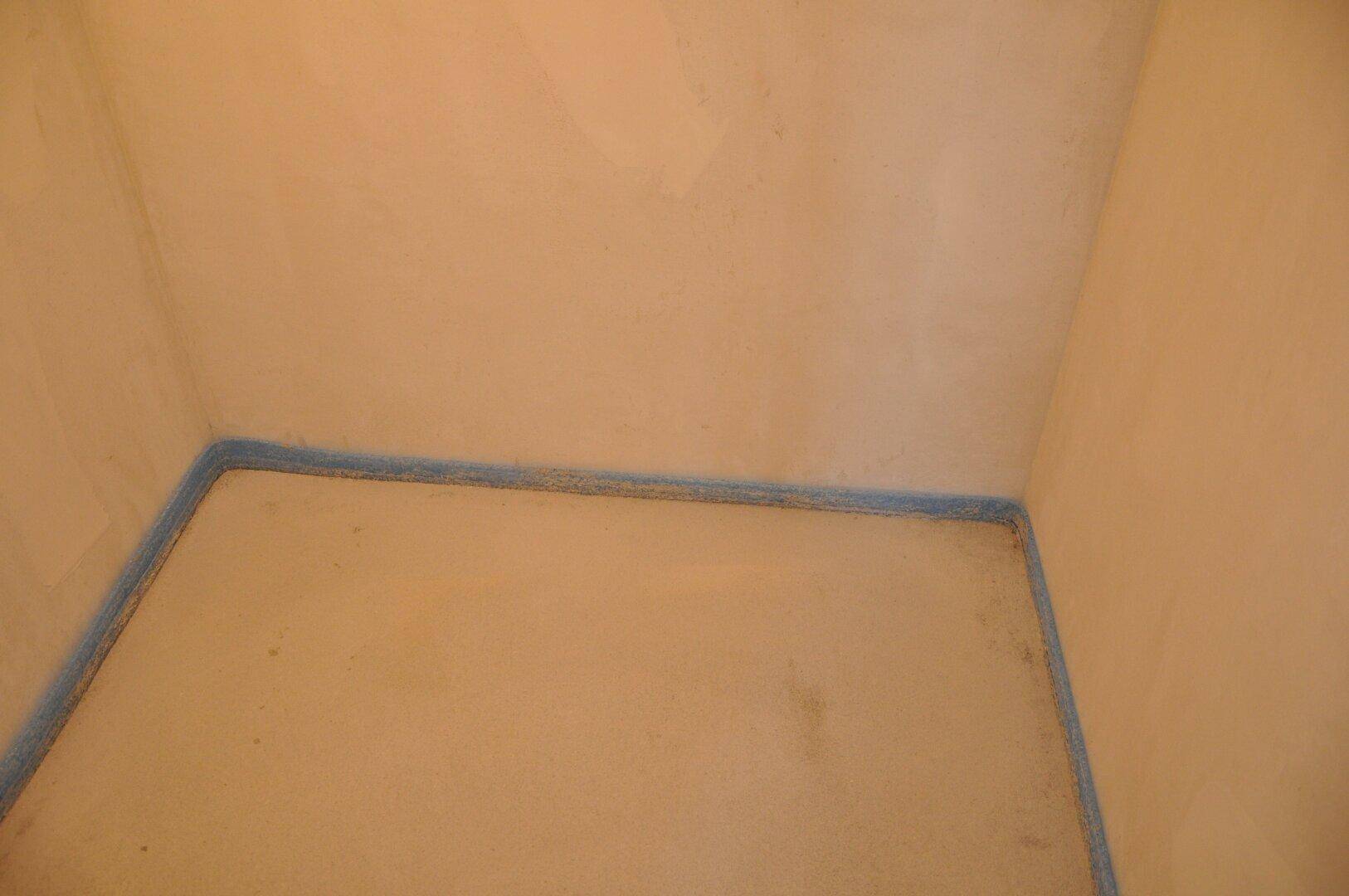 Ecke eines unfertigen Raumes mit Rohbauwänden und Estrichboden, bereit für den Ausbau.