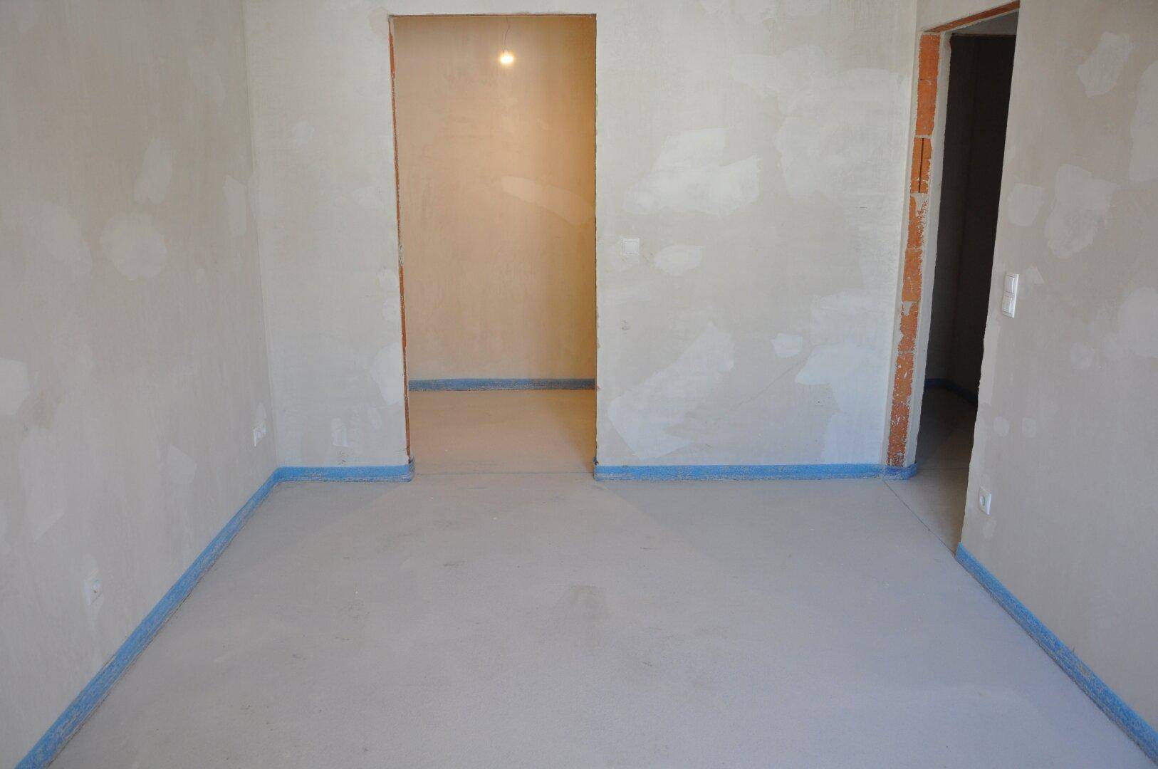 Unfertiger Raum mit zwei Türöffnungen und Rohbauwänden, ideal als Flur oder Durchgangszimmer.