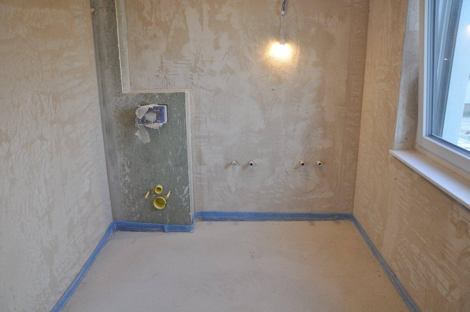 Unfertiges WC mit Fenster, Vorwandinstallation und vorbereiteten Anschlüssen für die Sanitäreinrichtung.