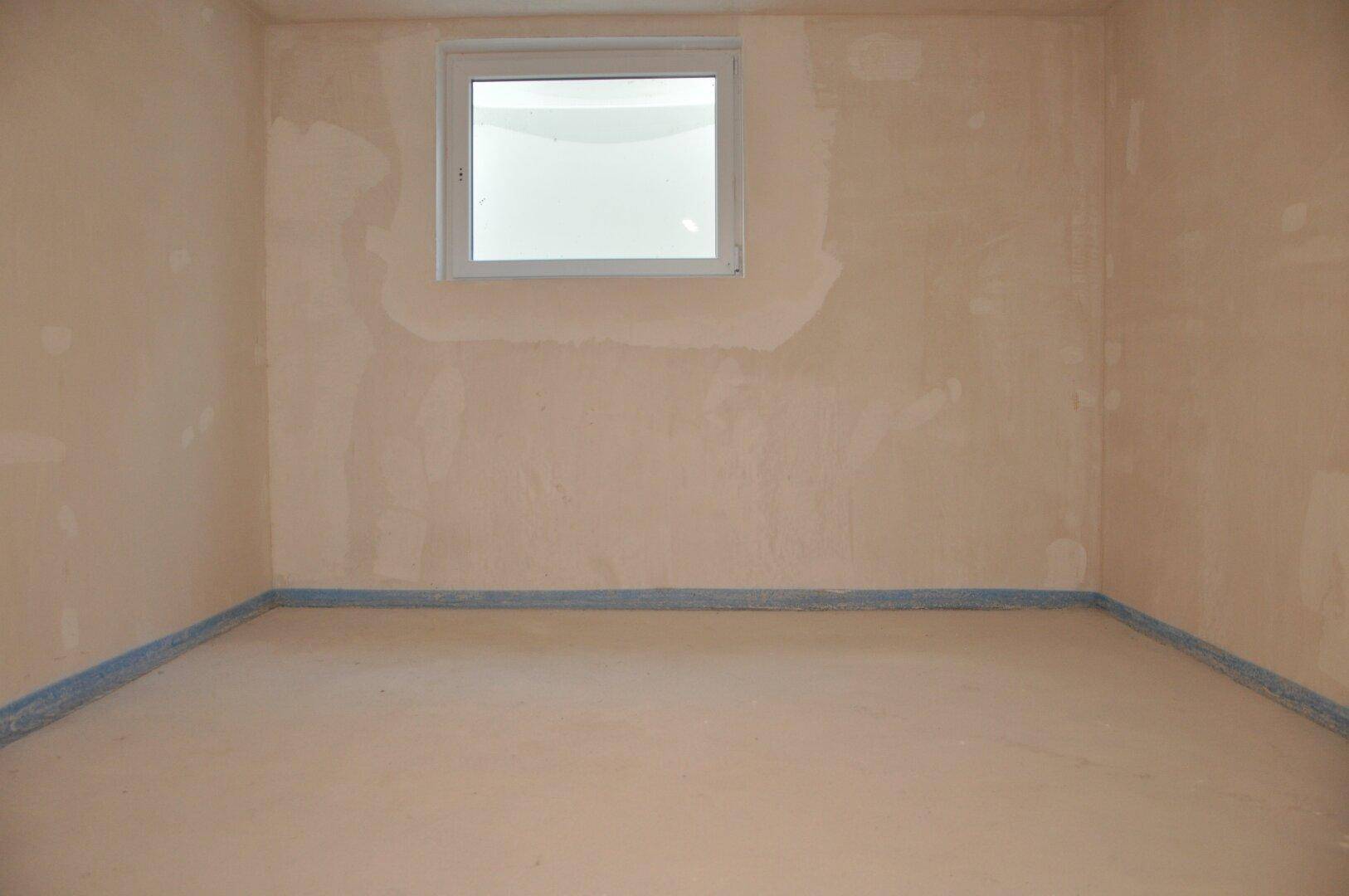 Unfertiger Kellerraum mit kleinem Fenster und Rohbauwänden, bietet zusätzlichen Stauraum.