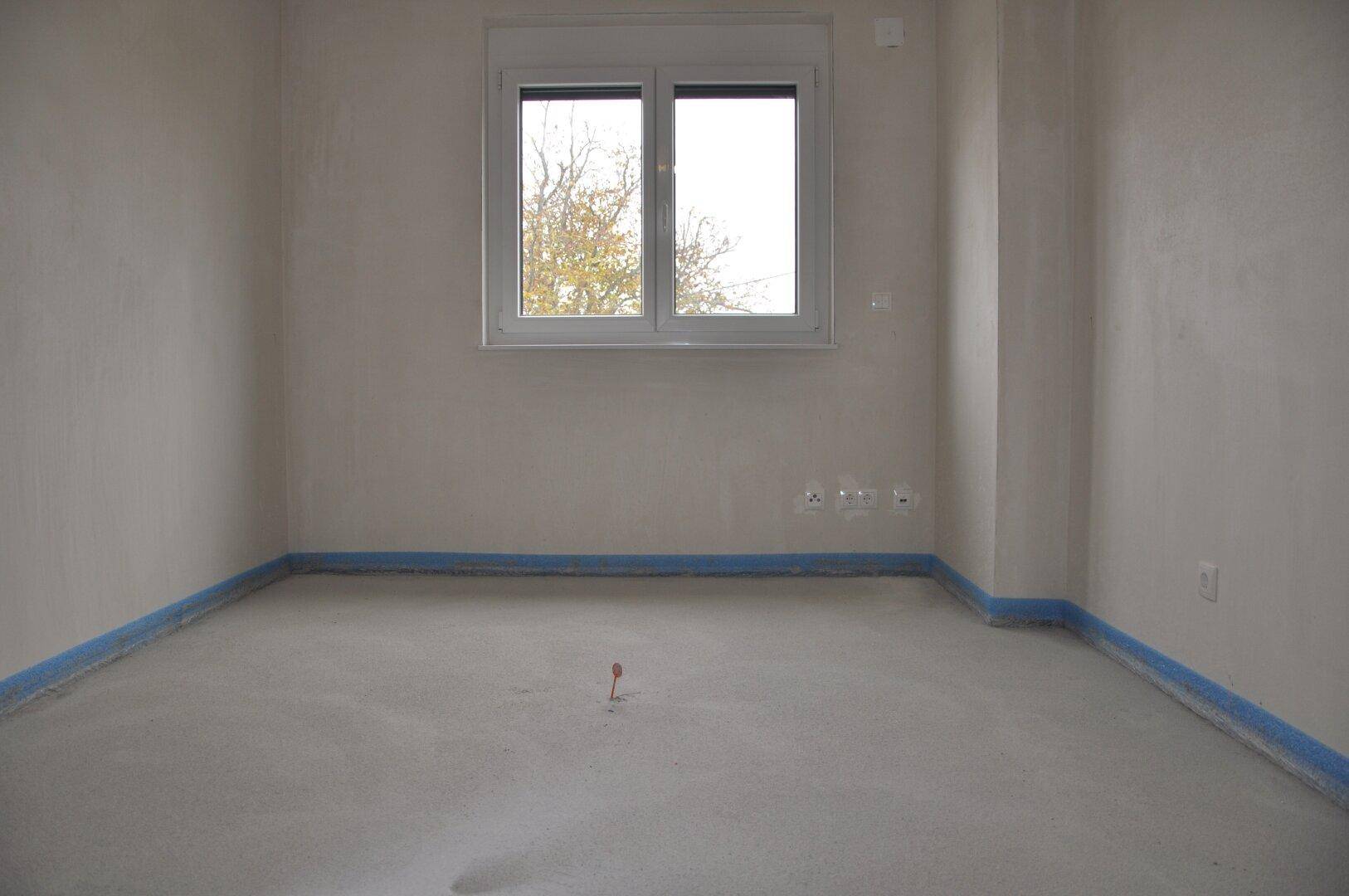 Unfertiger Raum mit Estrichboden und Fenster, ideal für ein Schlafzimmer oder Arbeitszimmer.
